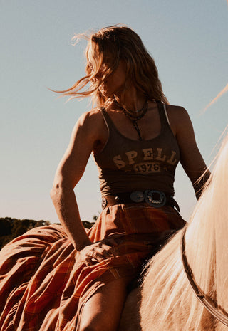  holding horse reins while the horse looks toward the camera under a clear blue sky.